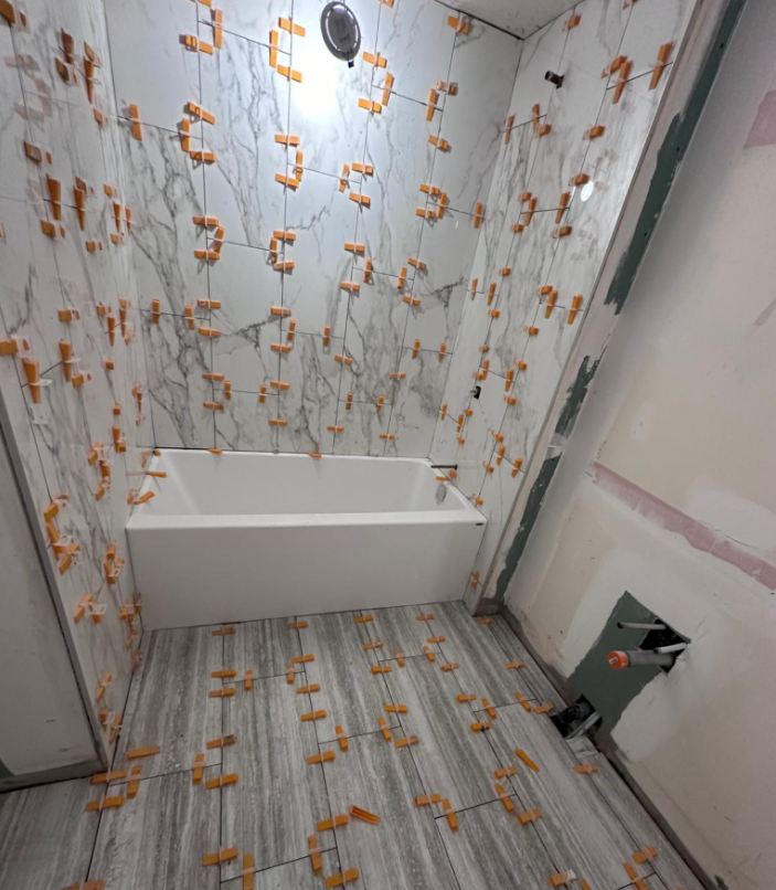 Bathroom mid-renovation with tile spacers in place and green moisture board exposed