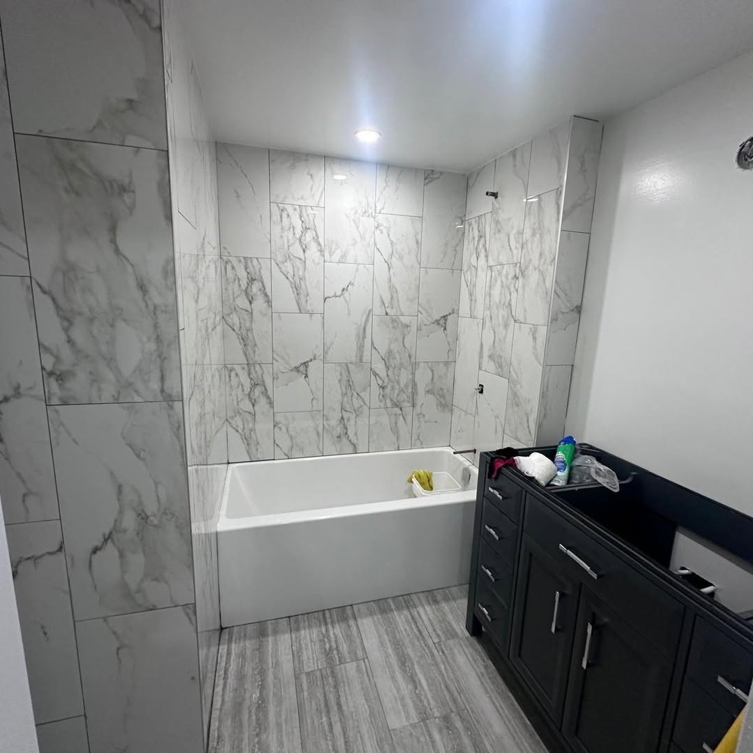 Renovated bathroom with marble-pattern tile shower surround and soaker tub