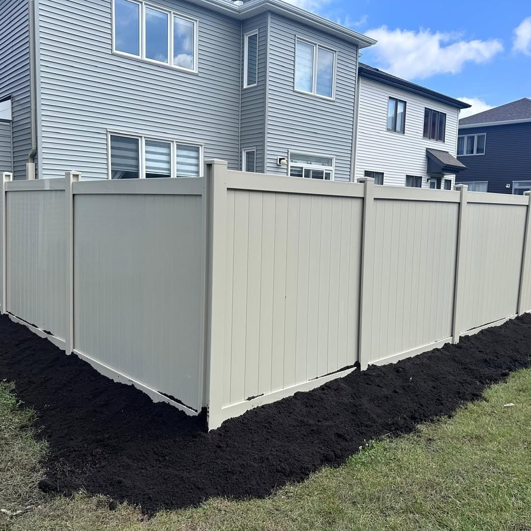 Cream-colored vinyl privacy fence with fresh mulch landscaping